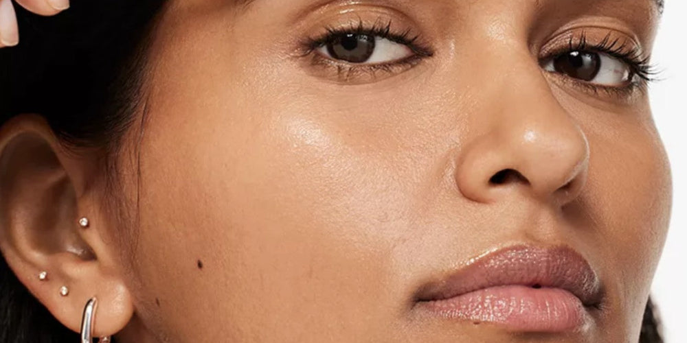 Woman holding a Clinique Just Browsing Brow Gel and brushing her eyebrows
