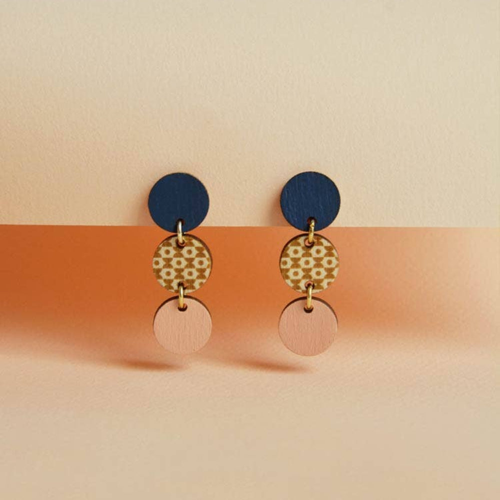 Pair of earrings with blue, gold, and pink circular designs on a two-tone background.