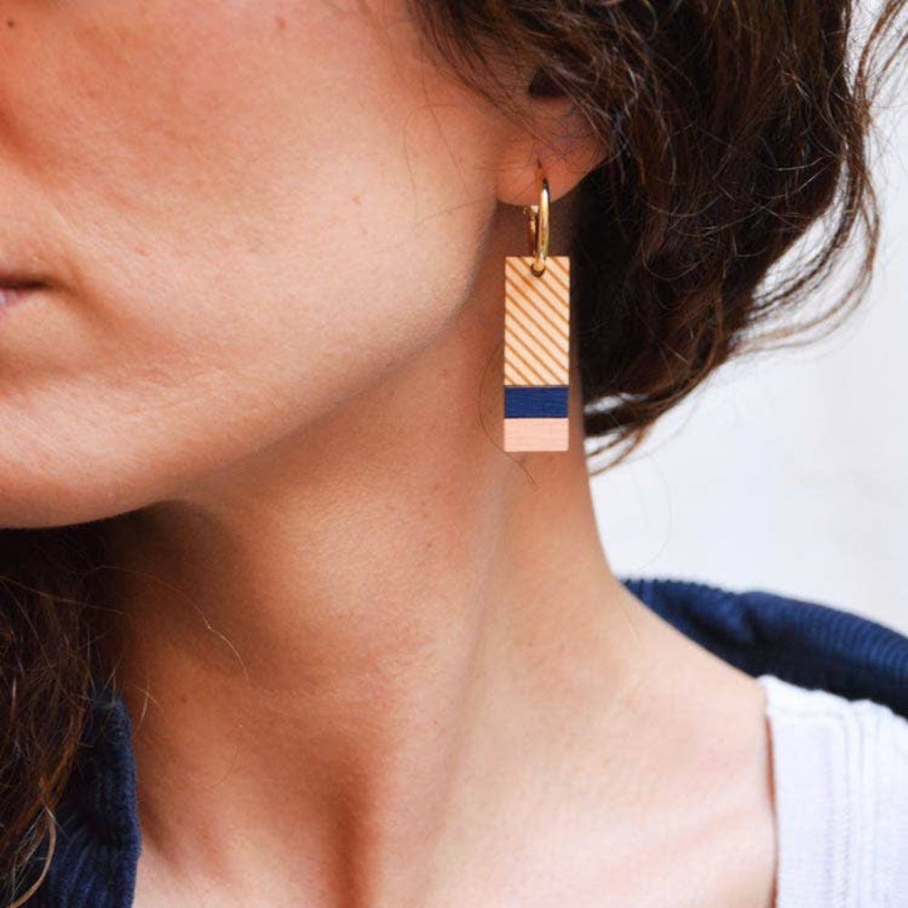 Close-up of a person wearing a gold earring with a blue accent.