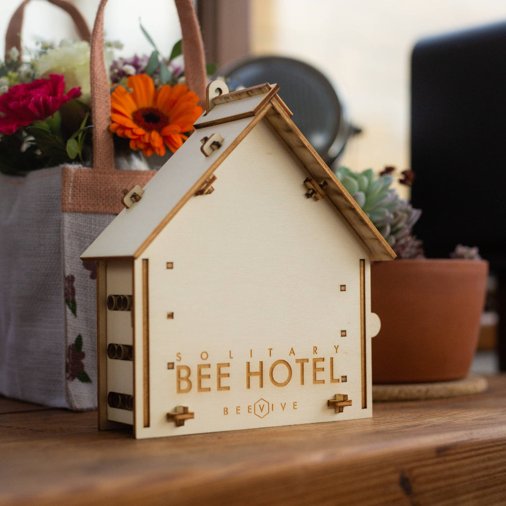 Wooden bee hotel with 'Solitary Bee Hotel' branding on a wooden surface.