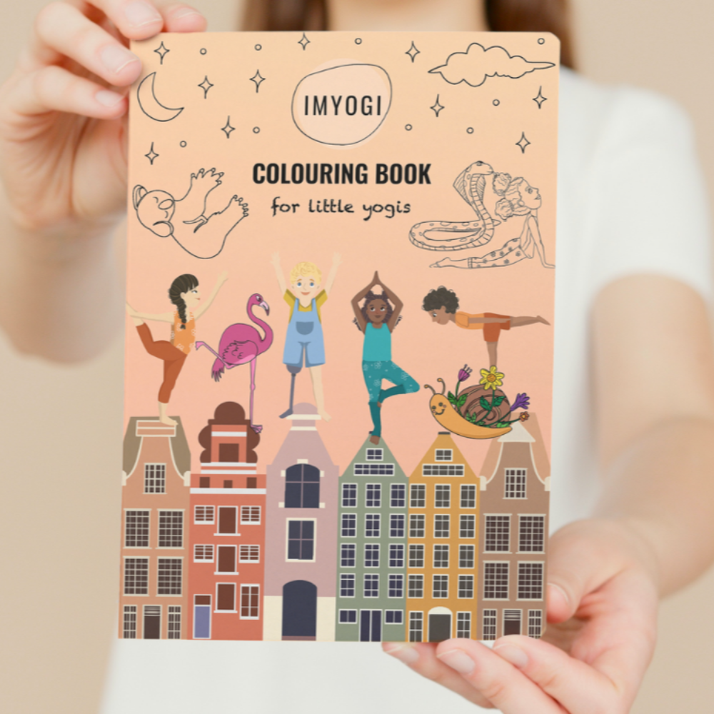 Person holding a 'Colours for Little Yogis' book with illustrations on a beige background