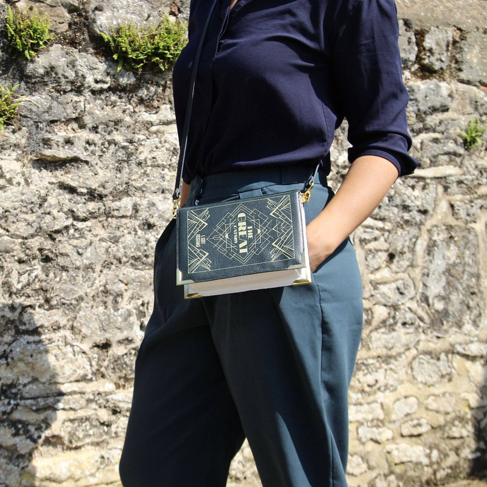 Person holding a book against a stone wall