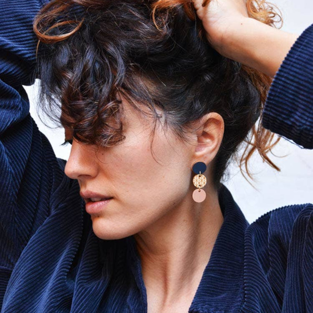 Woman wearing a blue jacket with a close-up of her earrings.
