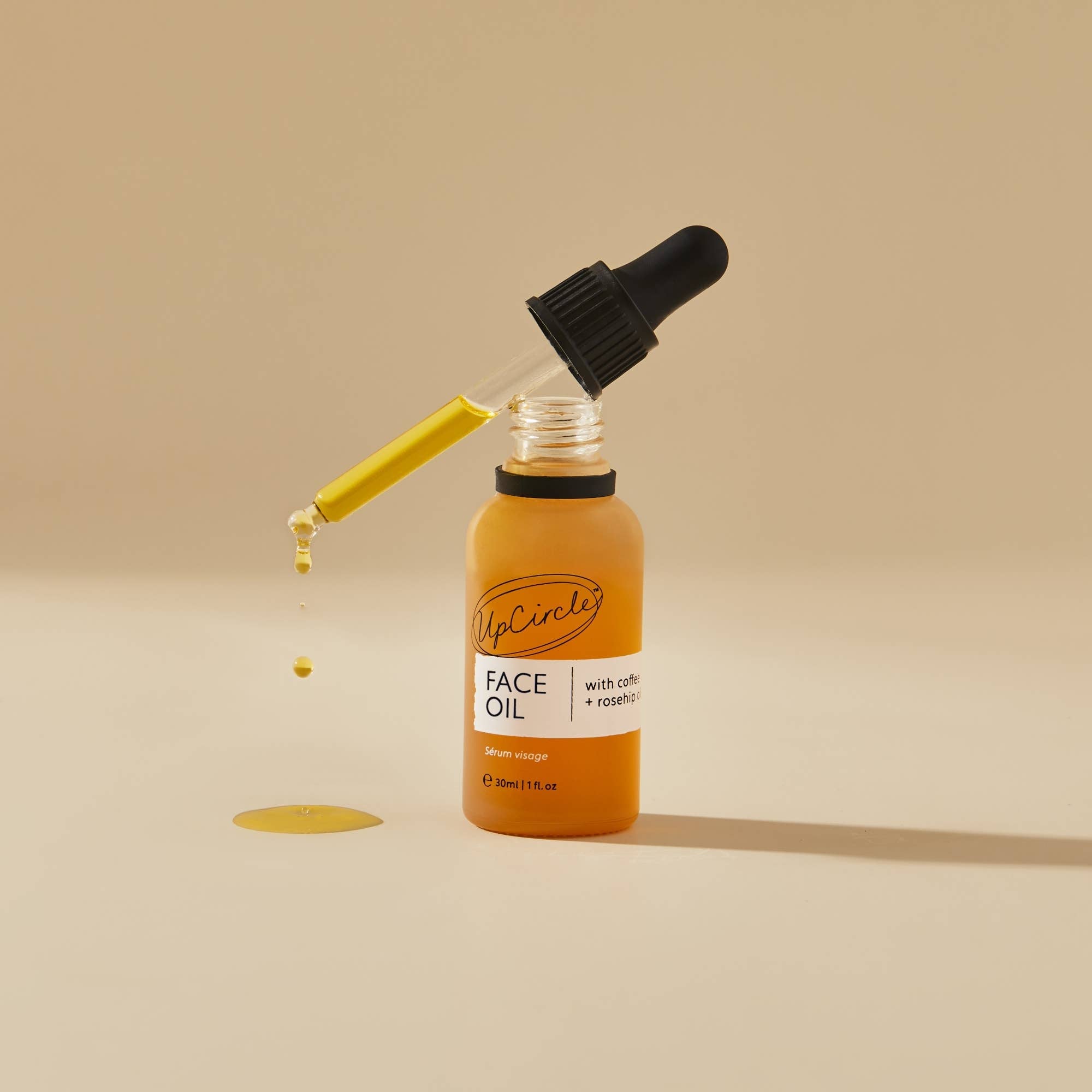 Bottle of face oil with a dropper on a beige background