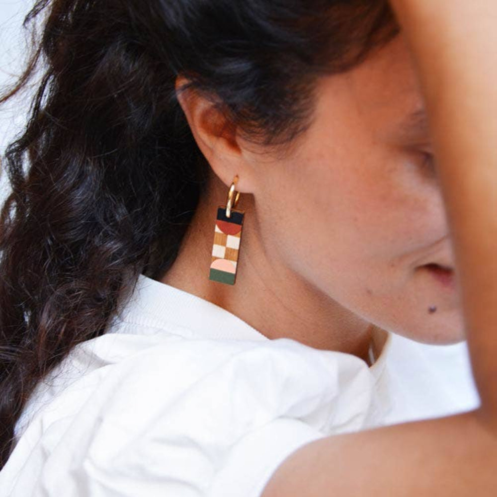 Close-up of a woman wearing colorful geometric earrings with a blurred background