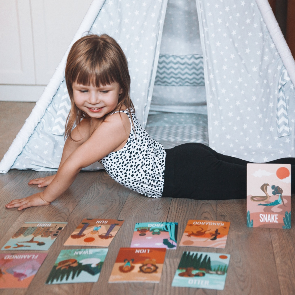 Child playing with educational cards on the floor next to a play tent.