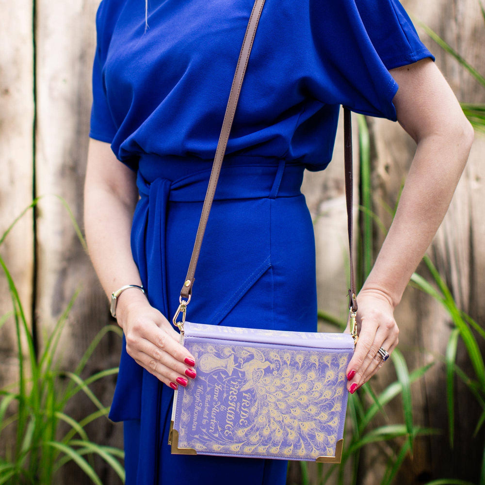 Person wearing a blue dress holding a decorative purple bag with a natural background