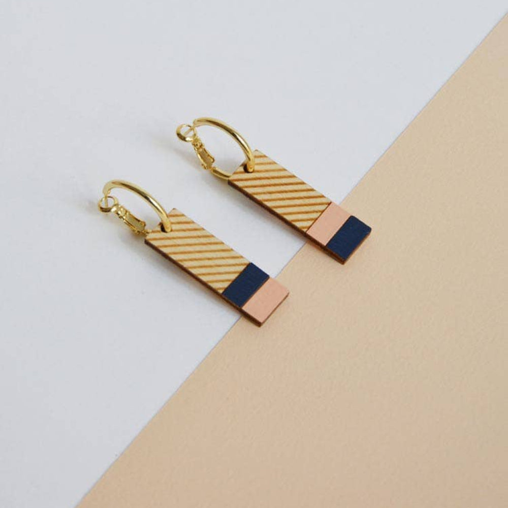 Gold and blue geometric earrings on a light gray and beige background