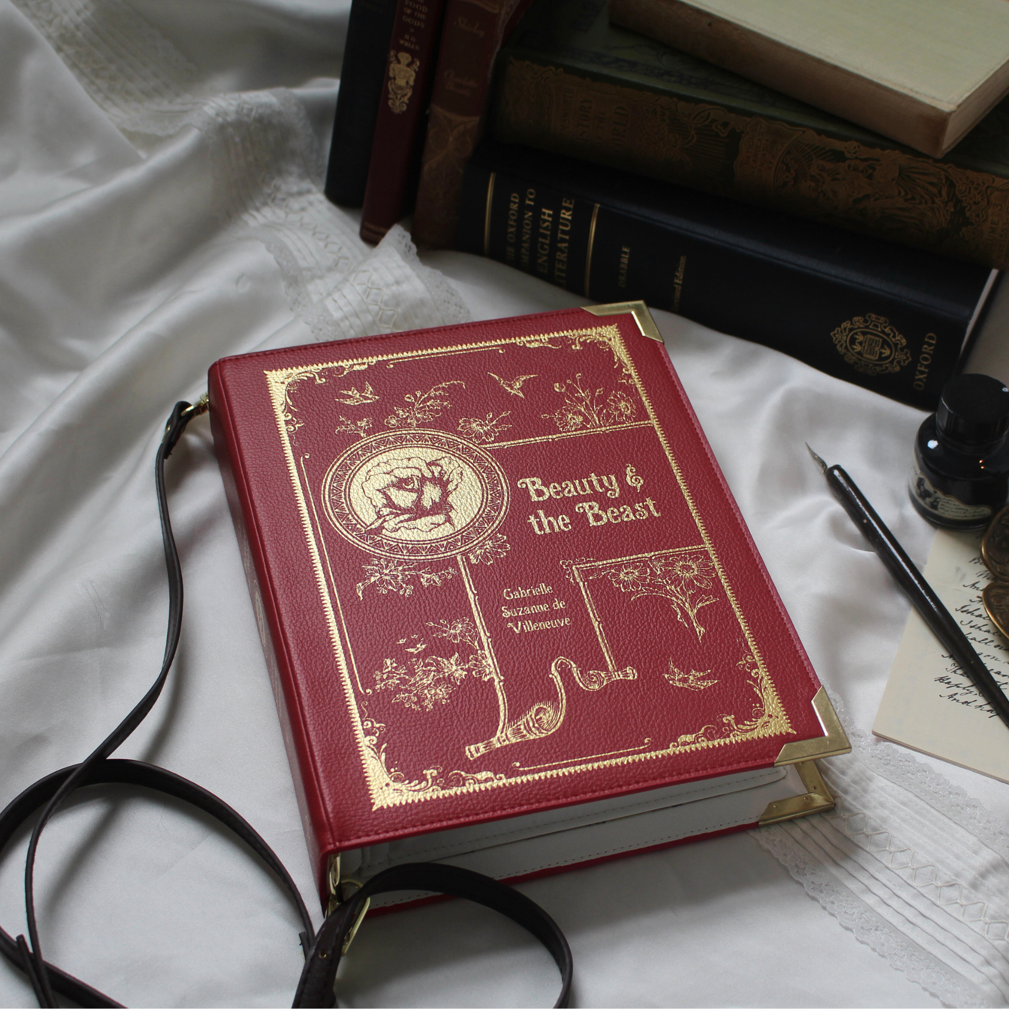 A red faux-leather crossbody bag designed to look like a vintage 'Beauty & the Beast' book, shown on a white background.