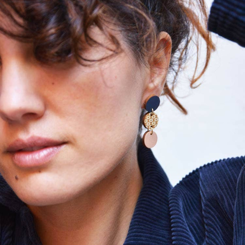 Close-up of a person wearing gold earrings with a blurred background