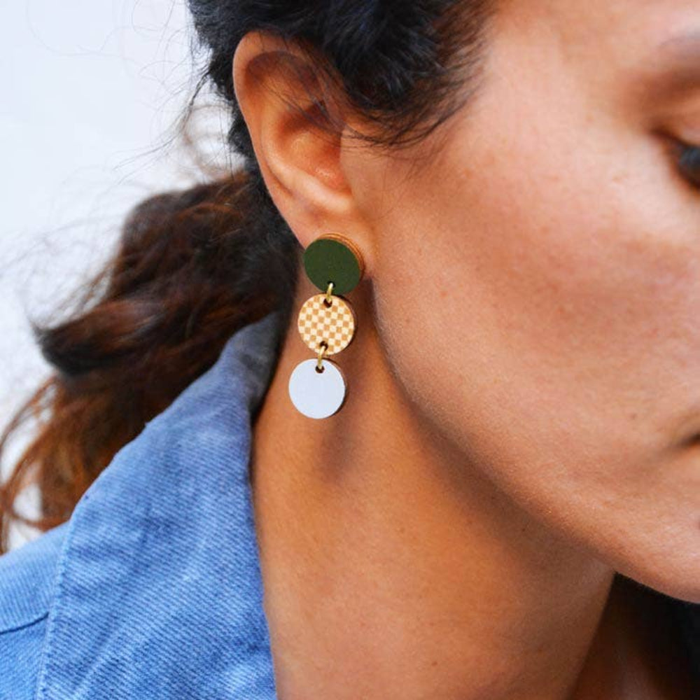 Close-up of a person wearing a green, gold, and white earring.