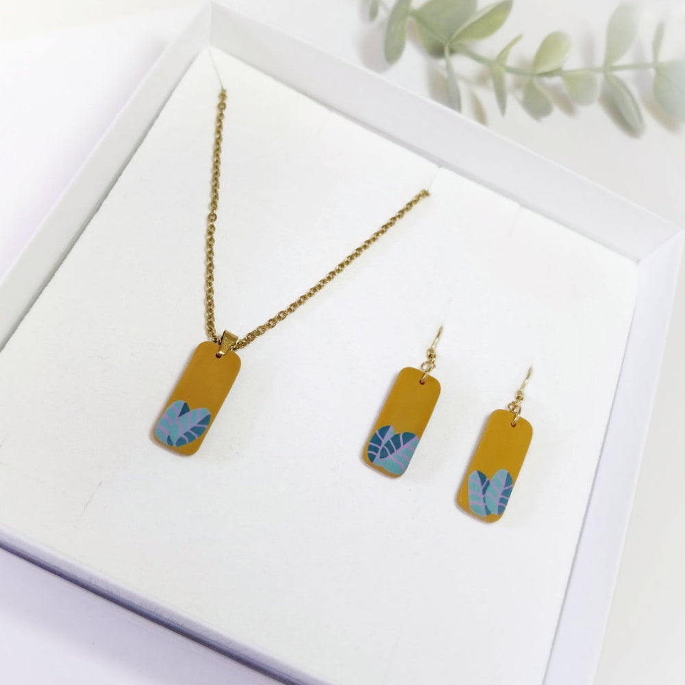 Gold necklace and earrings with blue leaf designs on a white background