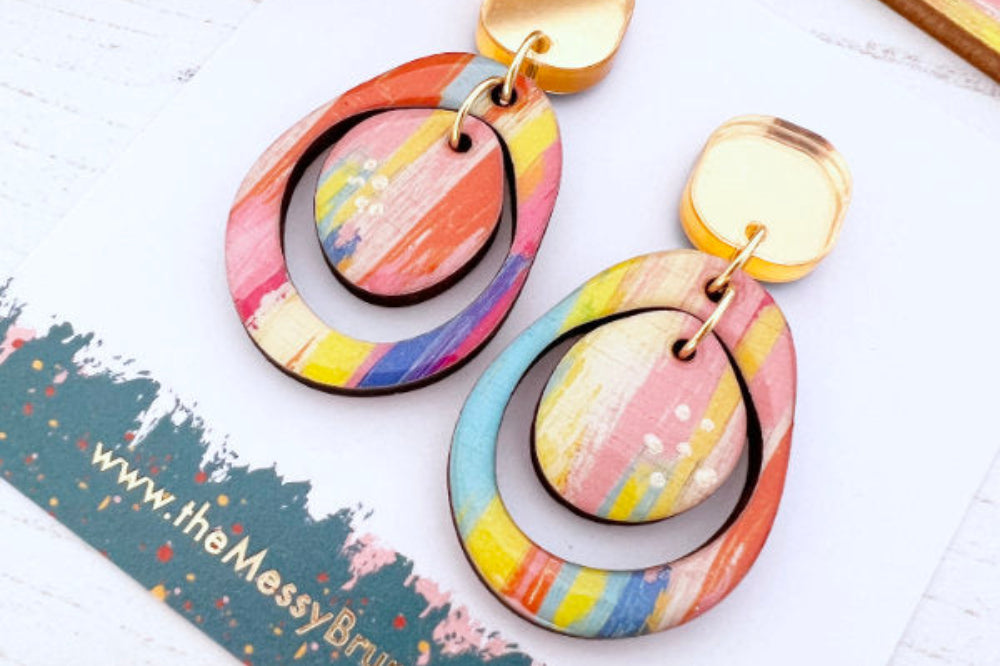 Colorful earrings on a white surface with a branded card underneath