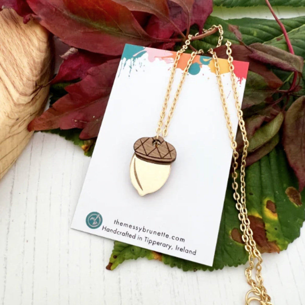 Gold acorn necklace on a card with leaves in the background