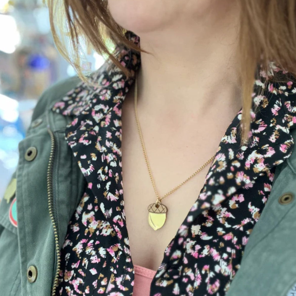 Person wearing a floral blouse with a green jacket and a gold necklace.