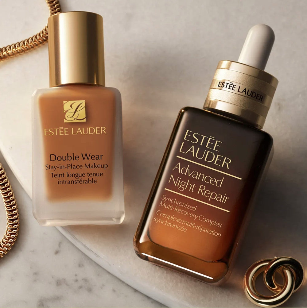 Estée Lauder Double Wear foundation and Advanced Night Repair serum on a marble surface.