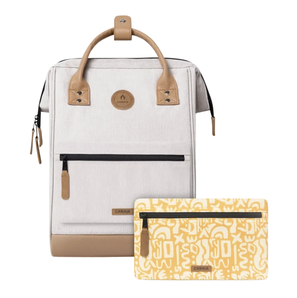 A light beige backpack with tan leather handles and trim, shown alongside a matching yellow patterned zip pouch on a plain white background. The brand name 'Cabaia' is visible on the circular front logo and the pouch.
