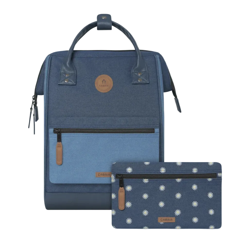 A blue and navy backpack with a matching zip pouch featuring a white daisy pattern, displayed on a clean off-white background. Both items have brown leather accents and a circular logo patch on the front.