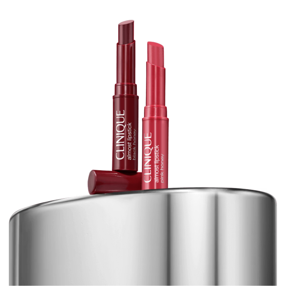 Two Clinique lipsticks on a metallic surface with a white background