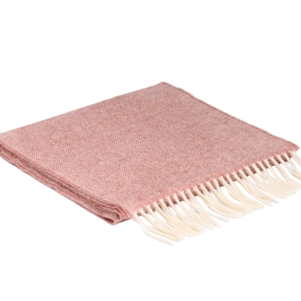 A folded pink scarf made of lambswool, with a herringbone pattern, displayed on a white background. The scarf has a fringed edge.