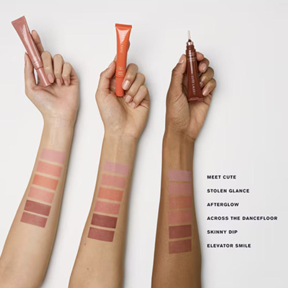 Three hands holding makeup products with color swatches on arms against a white background