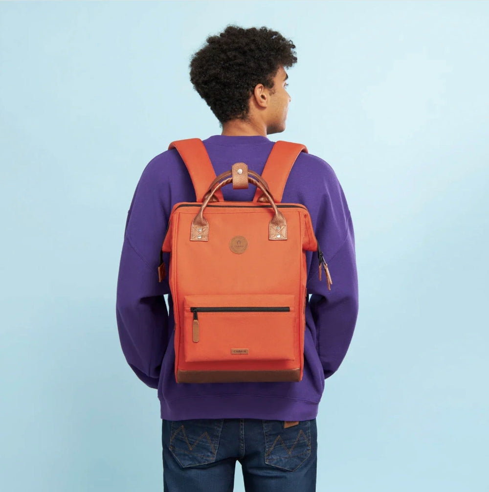Person wearing an orange backpack against a light blue background