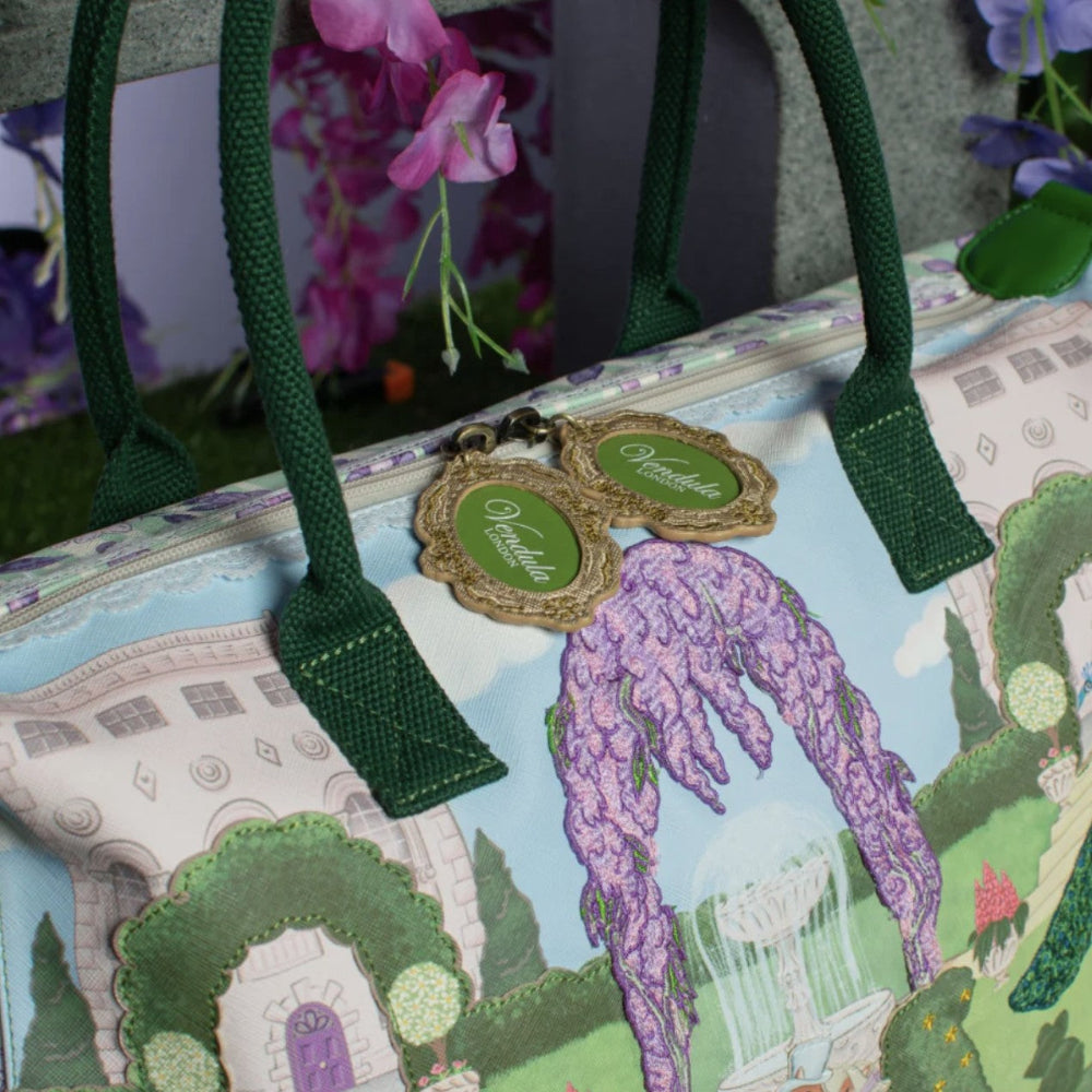 Handbag with garden design and green handles, featuring a brand tag.