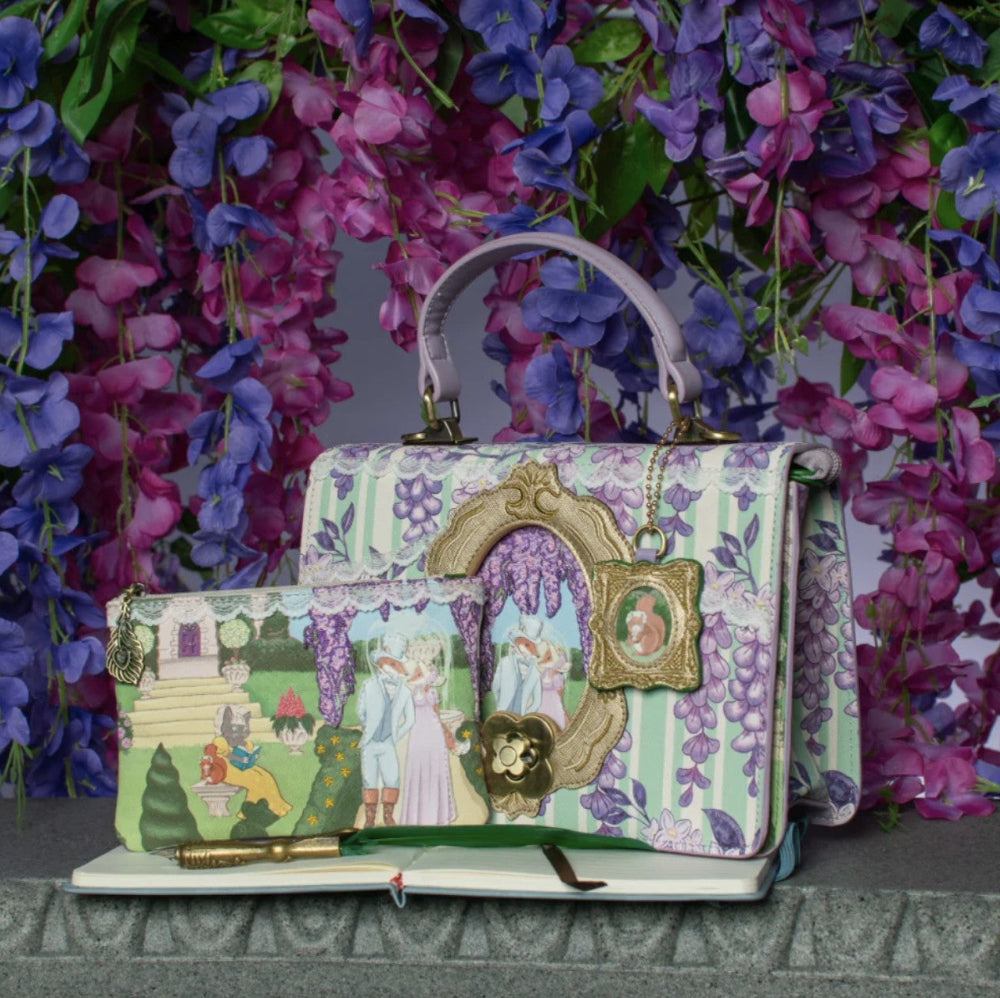Decorative handbag with fairy tale design against a floral background