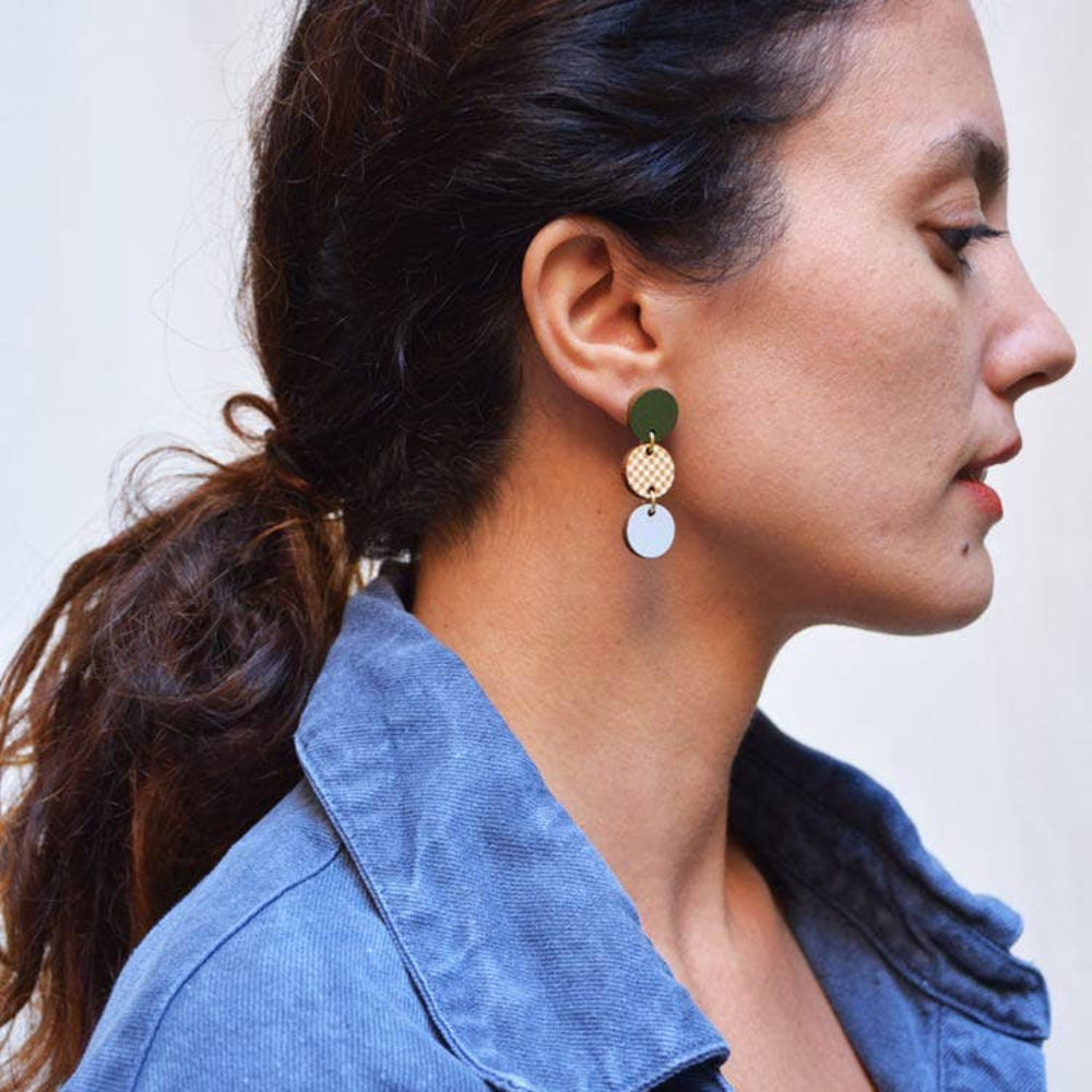 Woman wearing a blue denim jacket with earrings on a neutral background