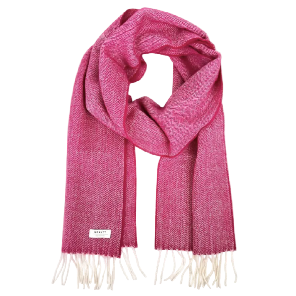 A pink and white herringbone patterned scarf with cream fringe, draped in a loop on a white background.