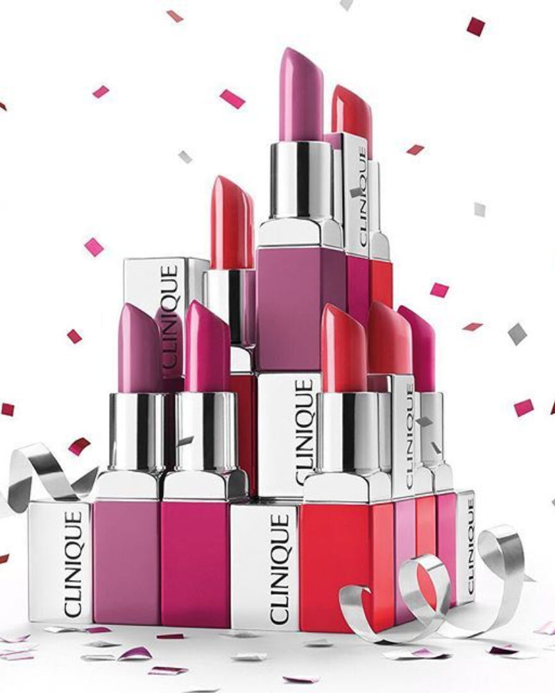 Stack of Clinique lipsticks with confetti on a white background