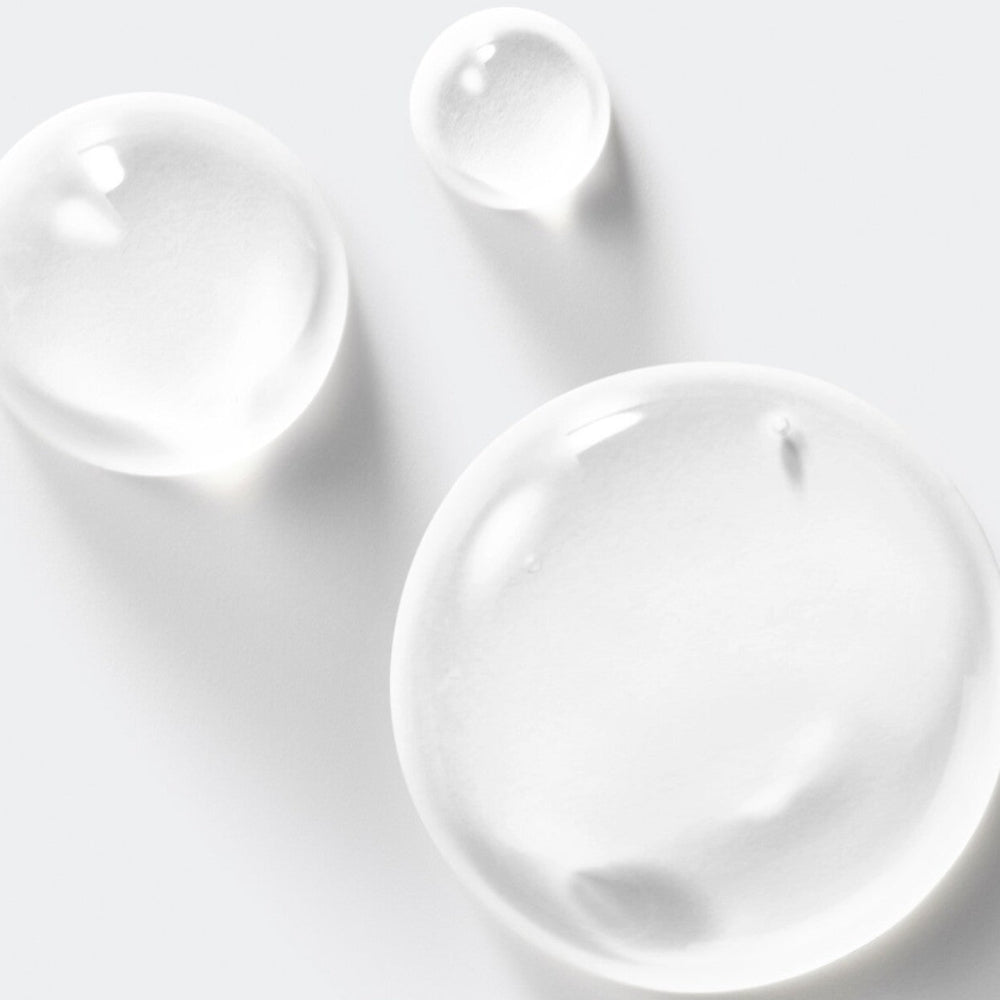 Three clear drops of salicylic acid on a light gray background