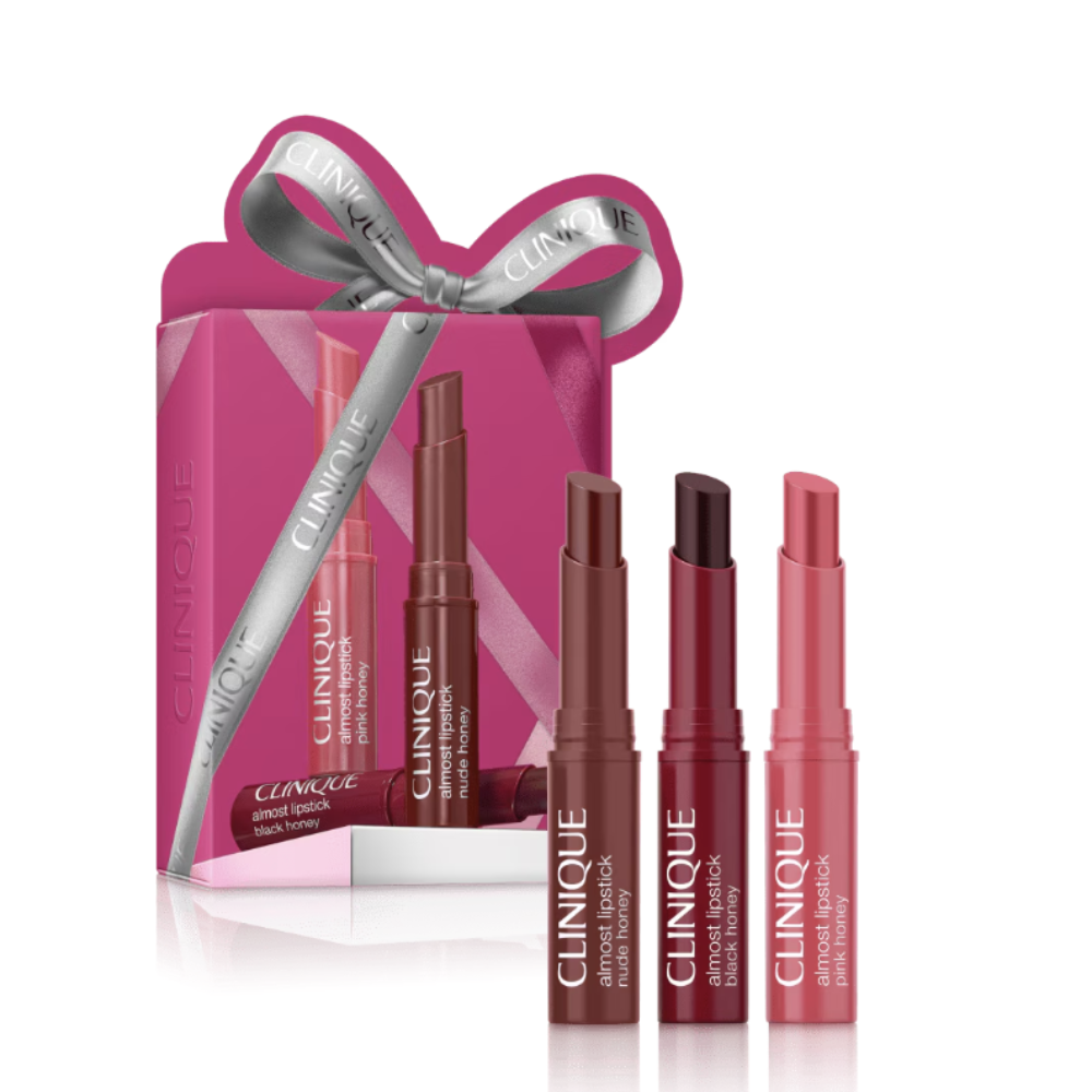 Clinique Almost Lipstick gift set featuring a pink box with a silver ribbon bow, three pink lipsticks displayed in front on a white background.