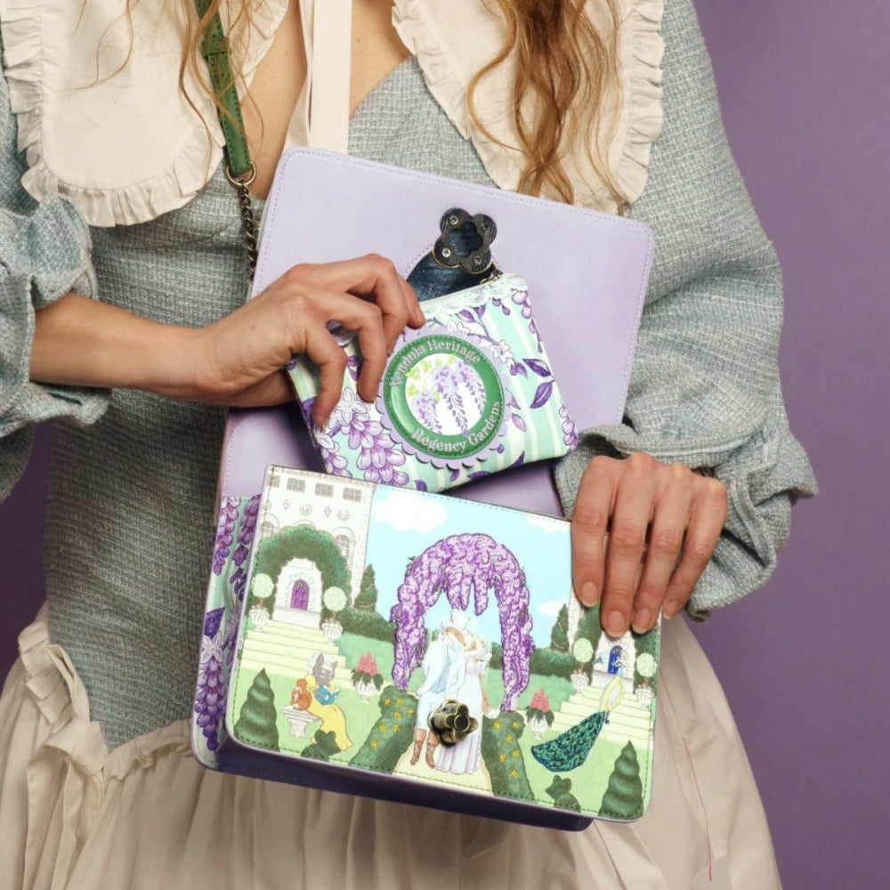 Person holding two colorful bags with garden-themed designs against a purple background