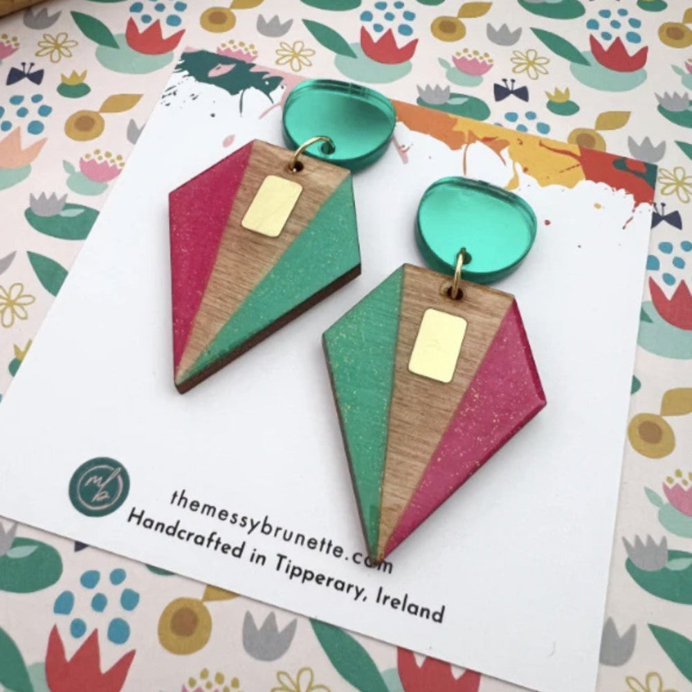 Geometric earrings on a colorful patterned card with 'themessybrunette' branding.