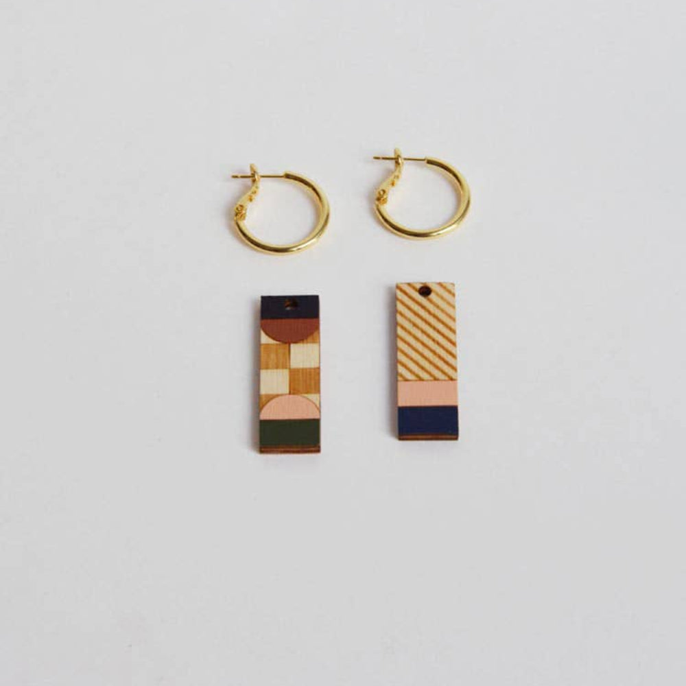 Gold hoop earrings with geometric pendant on a light gray background