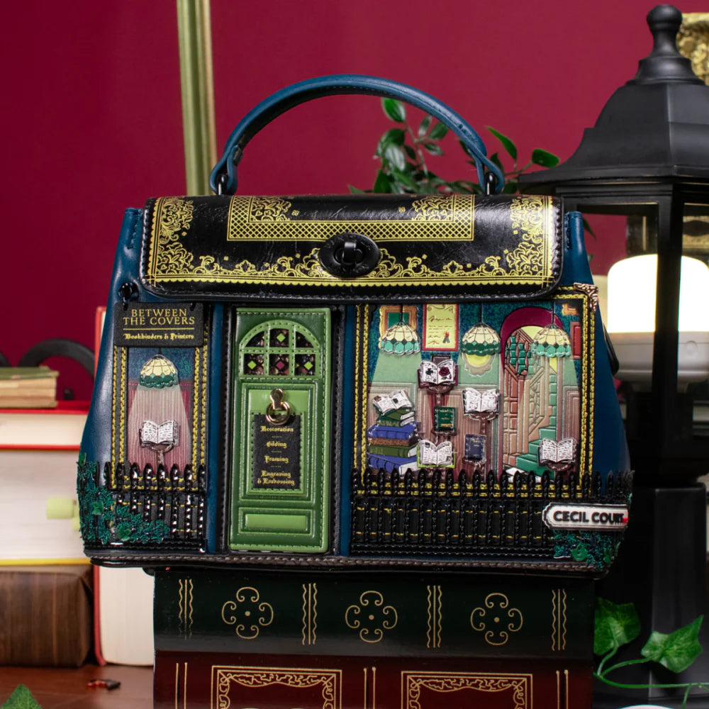 Decorative handbag with book-themed design on a red background