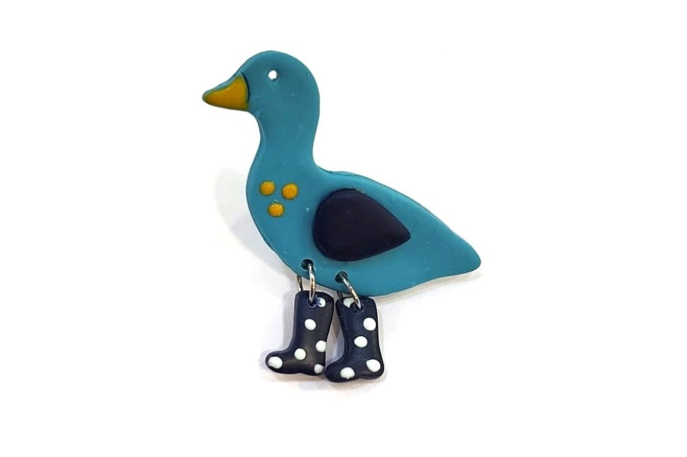 Blue duck-shaped brooch with a black heart on a white background