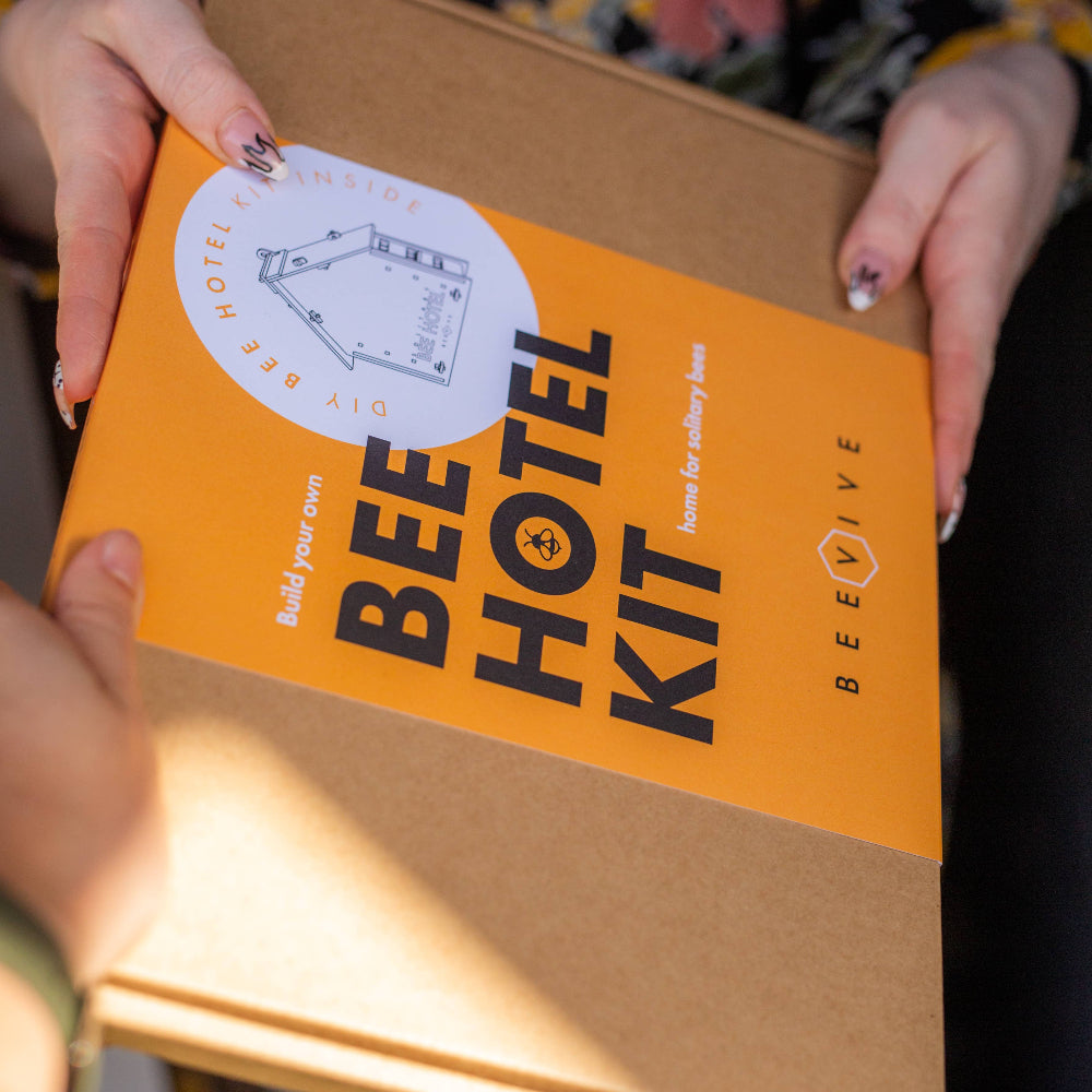 Bee Hotel Kit packaging held by a person with a floral background
