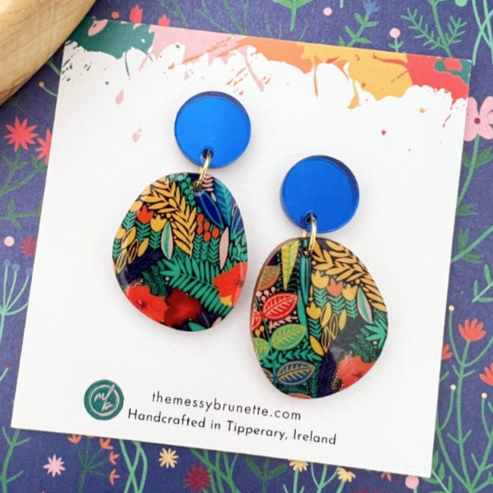 Colorful earrings on a branded card with a floral background