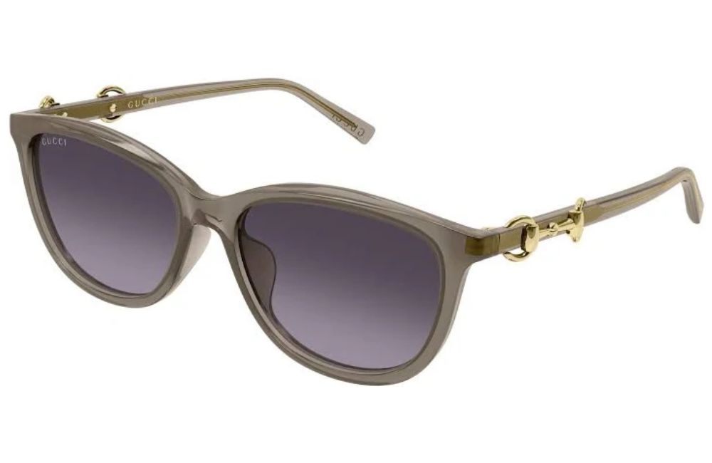 Gucci cat-eye sunglasses with a translucent taupe frame, gold-tone hardware, and gradient gray lenses, shown on a plain white background.