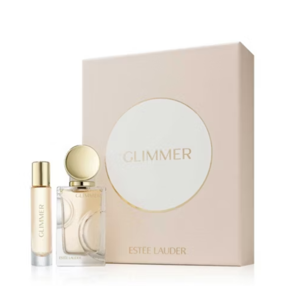 Estee Lauder Glimmer fragrance set featuring a small sample spray bottle and a larger bottle with gold accents, displayed in front of a pale pink rectangular box with a large white oval and gold 'GLIMMER' text.