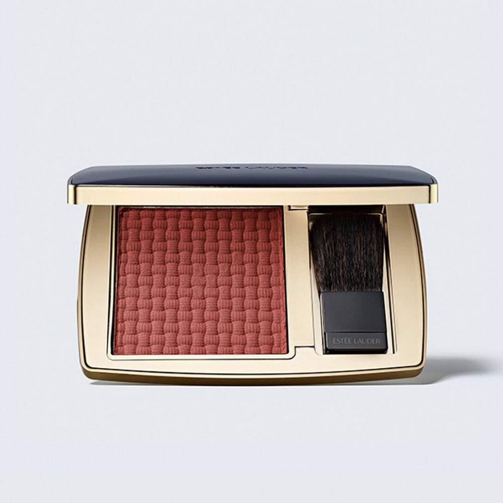 Estée Lauder blush compact with brush on a light gray background