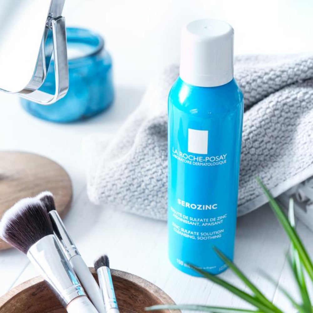 La Roche-Posay bottle with makeup brushes and a towel on a white surface