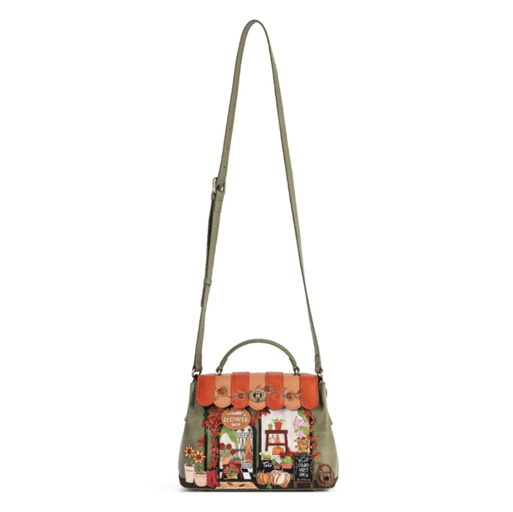 An olive green leather shoulder bag featuring a detailed autumn market scene patchwork applique on the front flap, complete with orange awnings, pumpkins, and a small top handle, shown against a plain white background.