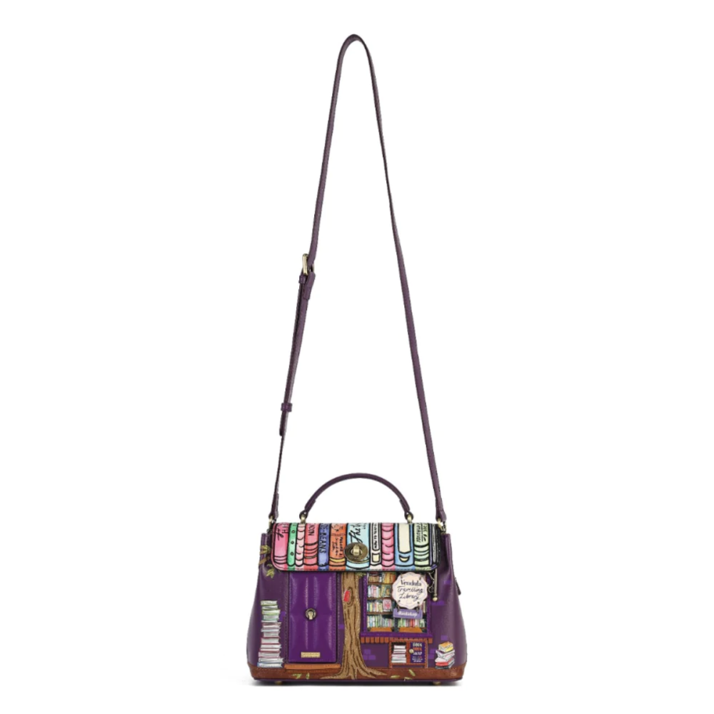 A purple leather handbag with a colorful book-themed illustration on the front flap and a long shoulder strap, shown against a plain white background.