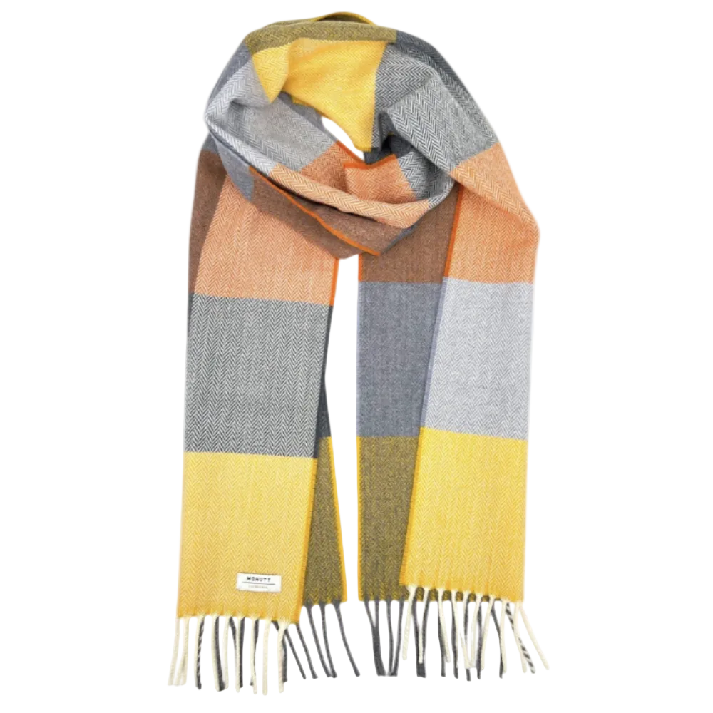 A multicolor block-check scarf with a herringbone texture, featuring large squares of yellow, gray, orange, and olive green, finished with white and black fringe.