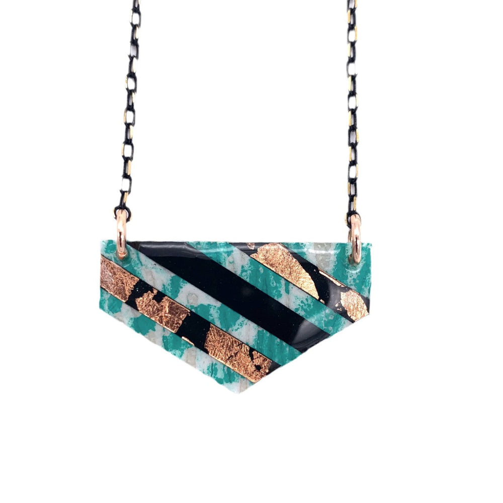 Necklace with a geometric pendant featuring turquoise, black, and gold colors on a white background.