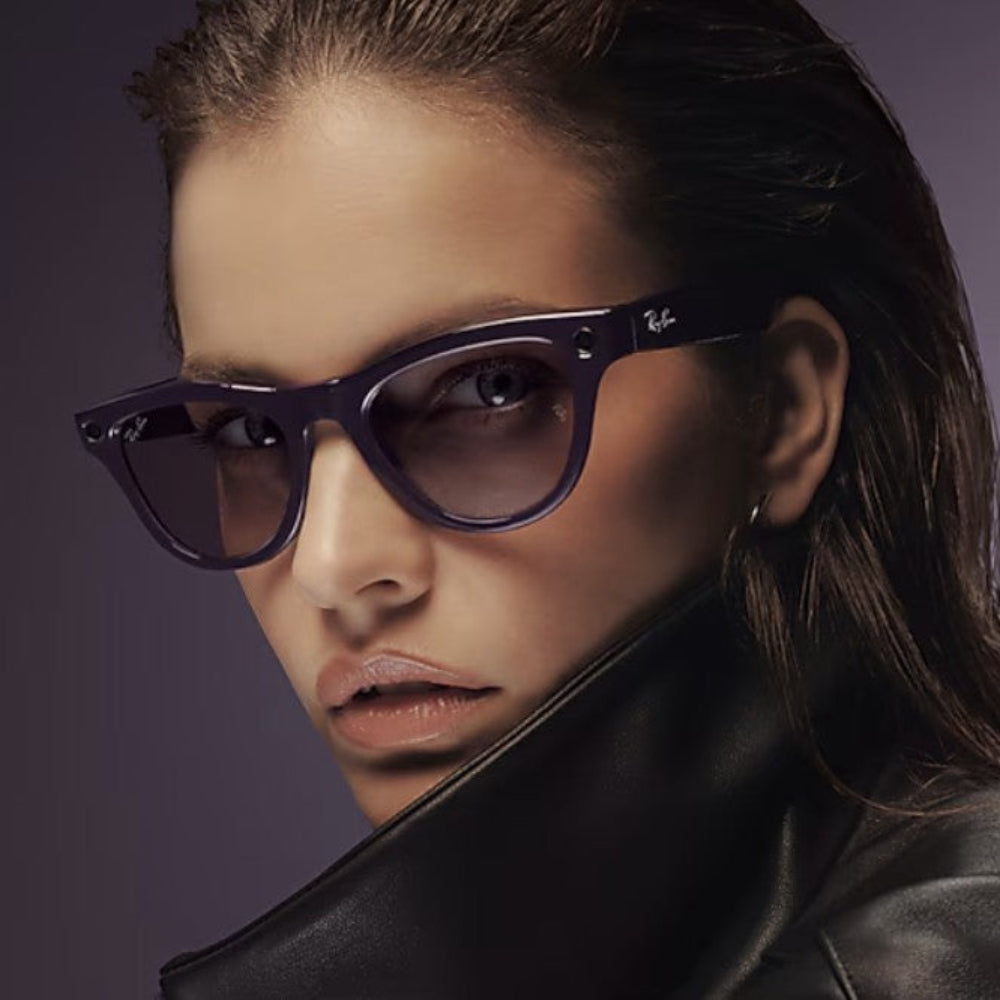Woman wearing a black leather jacket and sunglasses against a dark background
