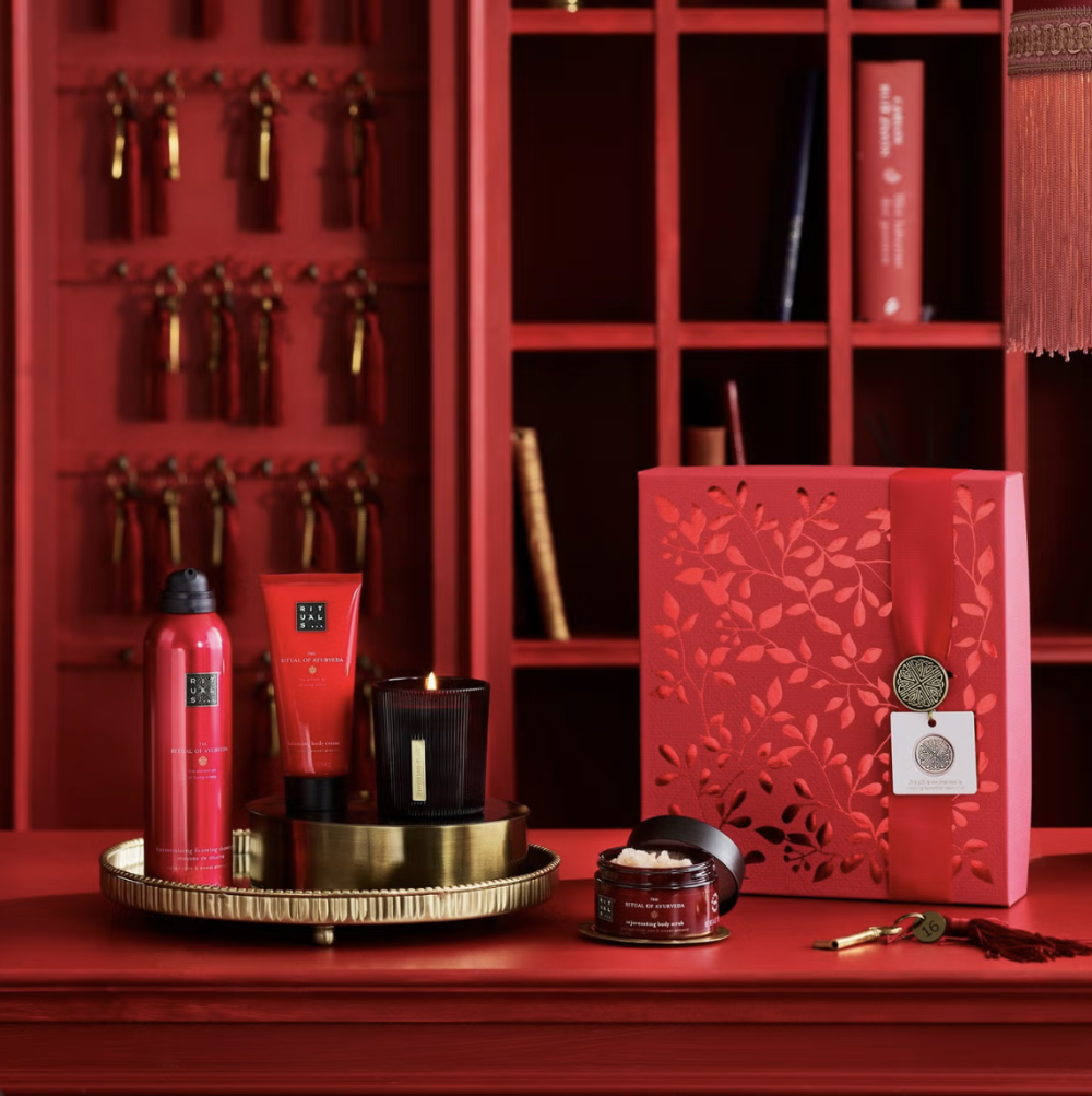 Red cosmetic products and packaging on a red surface with a decorative background.
